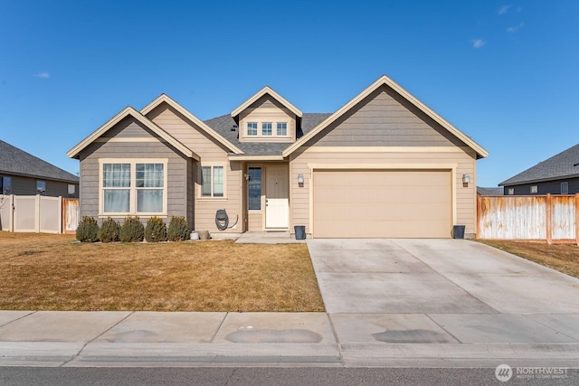 view of front of home featuring an attached garage, driveway, fence, and a front yard