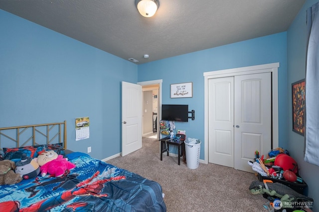 bedroom with a textured ceiling, carpet floors, visible vents, baseboards, and a closet