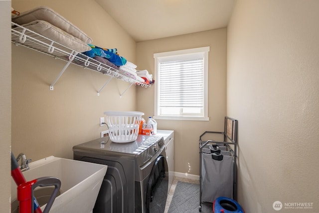 laundry area featuring laundry area, washing machine and dryer, baseboards, and a sink