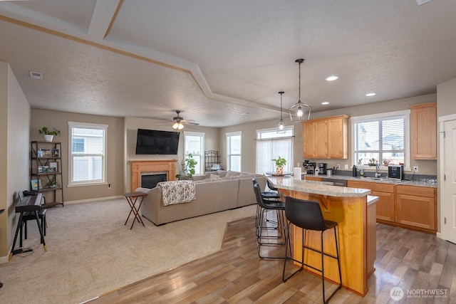 kitchen with light countertops, light brown cabinetry, a fireplace, and a kitchen bar