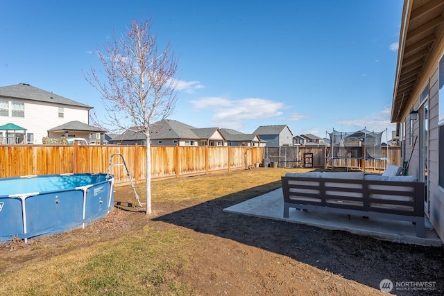 view of yard with a patio, a fenced backyard, a residential view, a fenced in pool, and a trampoline