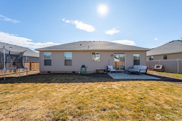 back of house featuring a lawn, a patio, a fenced backyard, crawl space, and a trampoline