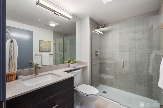 full bathroom featuring a stall shower, vanity, and toilet