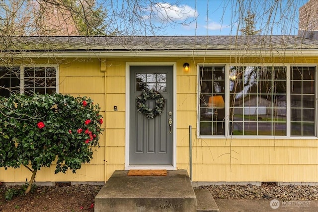 property entrance featuring crawl space and a shingled roof