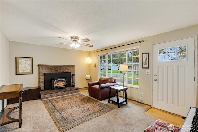 living area with baseboards, a textured ceiling, a ceiling fan, and carpet