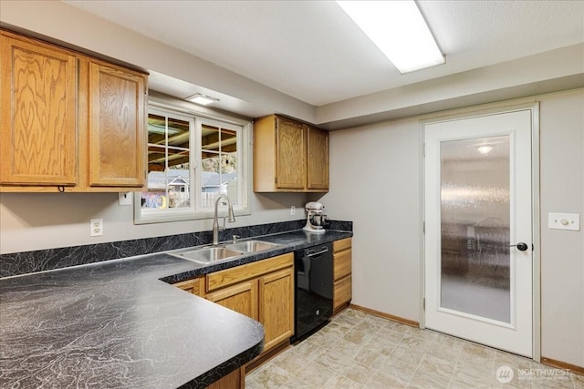 kitchen featuring dark countertops, baseboards, black dishwasher, brown cabinets, and a sink