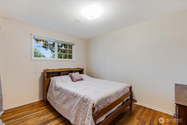 bedroom with baseboards, a textured ceiling, and wood finished floors