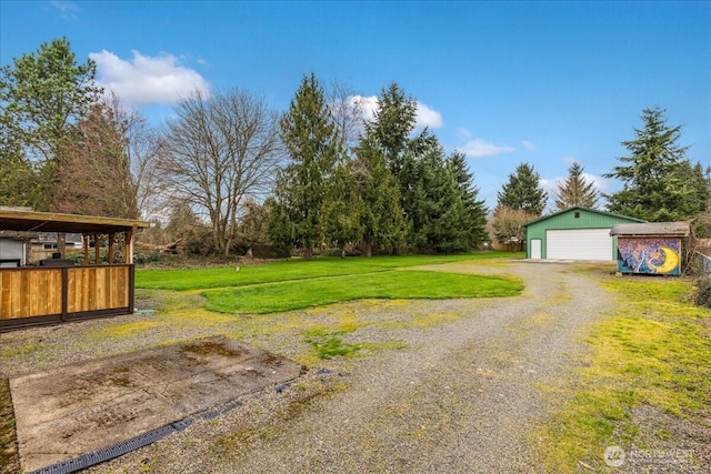 view of yard featuring a garage, an outbuilding, and driveway