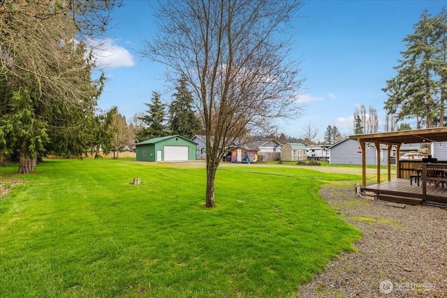 view of yard with an outdoor structure, a garage, driveway, and a wooden deck