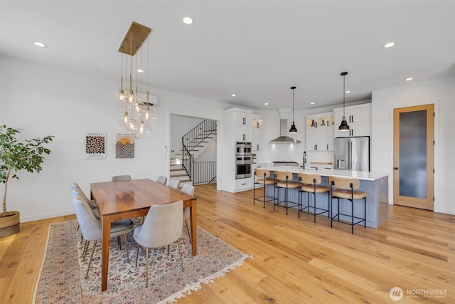 dining space featuring recessed lighting, light wood-type flooring, and stairs