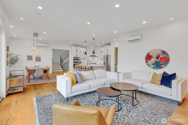 living room featuring light wood finished floors, stairs, and a wall mounted AC