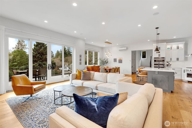 living room featuring recessed lighting, light wood-style flooring, and a wall unit AC