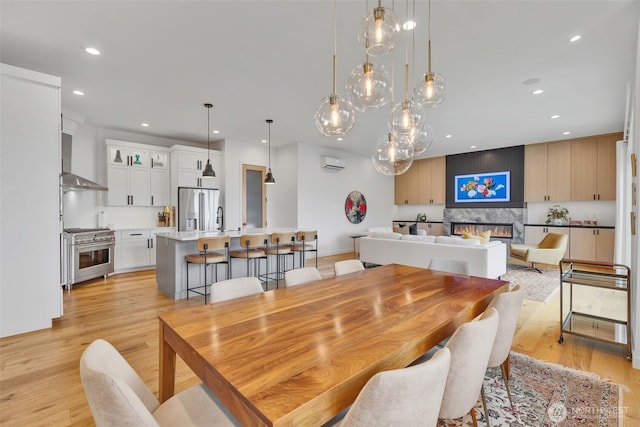 dining room with light wood finished floors, recessed lighting, and a fireplace