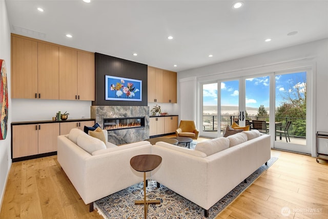 living area with recessed lighting, light wood-type flooring, and a premium fireplace