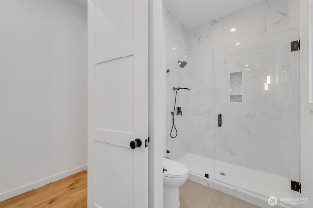 full bathroom with toilet, wood finished floors, baseboards, and a marble finish shower