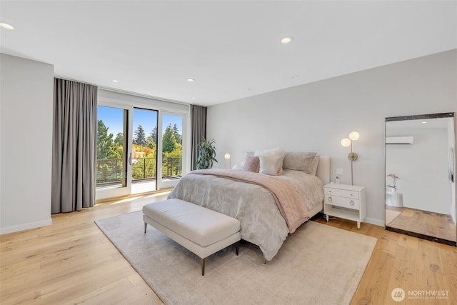 bedroom with recessed lighting, baseboards, light wood-style flooring, and a wall mounted AC