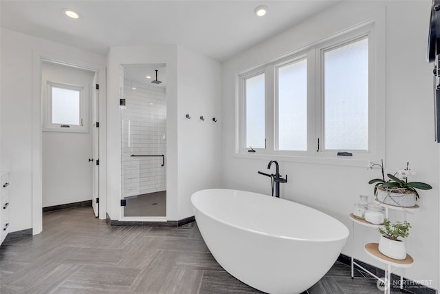 bathroom featuring recessed lighting, a freestanding tub, baseboards, and a shower stall