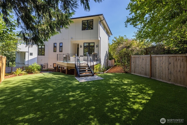 back of property featuring a deck, a lawn, and a fenced backyard