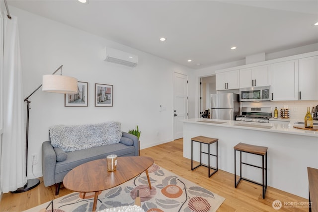 living room with light wood finished floors, recessed lighting, baseboards, and a wall unit AC