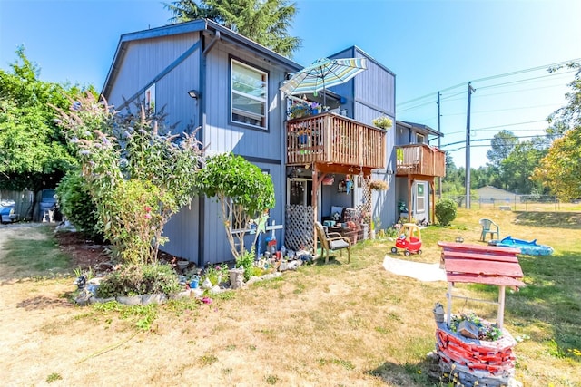 rear view of property featuring a deck and a lawn