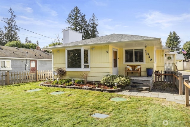 view of front of property featuring a shingled roof, a chimney, fence, and a front yard