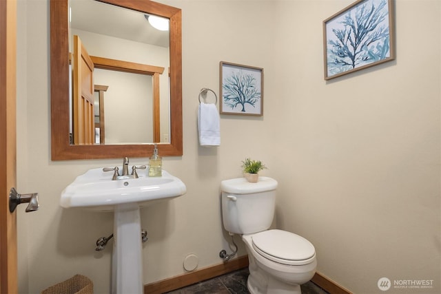 bathroom featuring toilet, baseboards, and a sink