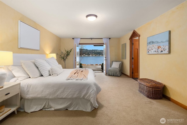 carpeted bedroom with access to exterior, a water view, and baseboards