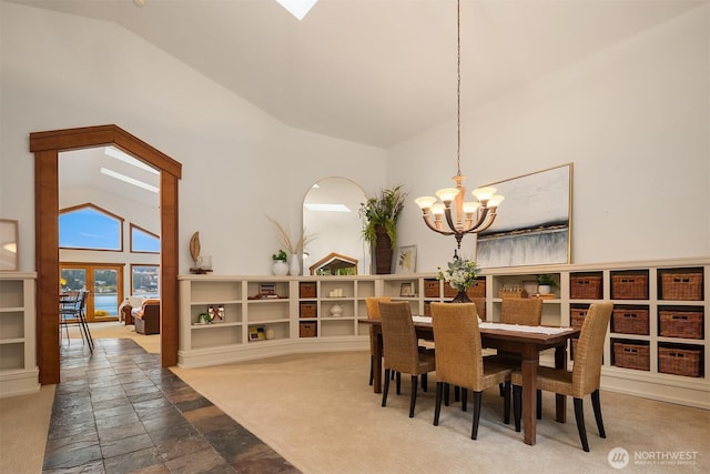 dining room with high vaulted ceiling, french doors, a notable chandelier, and stone tile floors