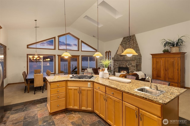 kitchen featuring a stone fireplace, a sink, light stone countertops, and stainless steel gas stovetop