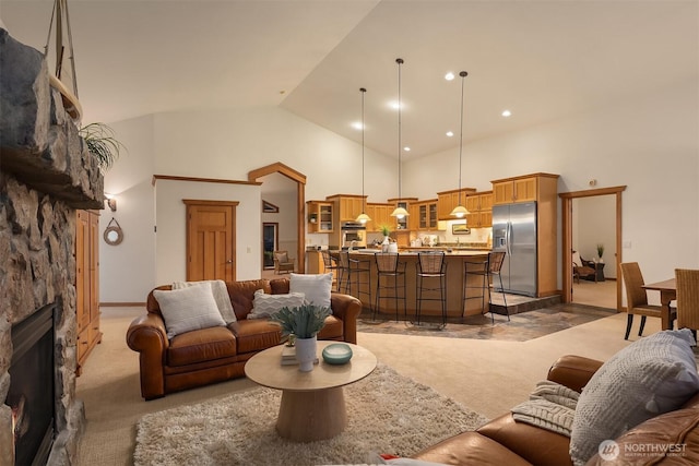 living area featuring light carpet, recessed lighting, high vaulted ceiling, and a stone fireplace