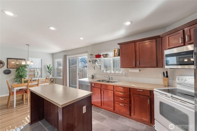 kitchen featuring light countertops, appliances with stainless steel finishes, a sink, and a center island