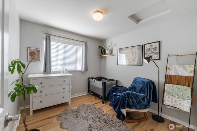 living area featuring light wood-style floors, attic access, and baseboards