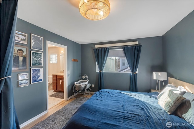 bedroom featuring light wood-style flooring, baseboards, and ensuite bathroom