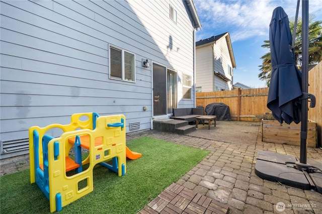 exterior space with a patio area, a playground, and fence