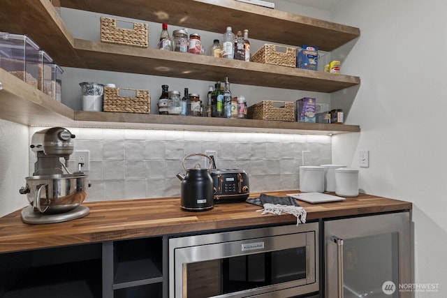 bar with a dry bar, stainless steel microwave, and decorative backsplash