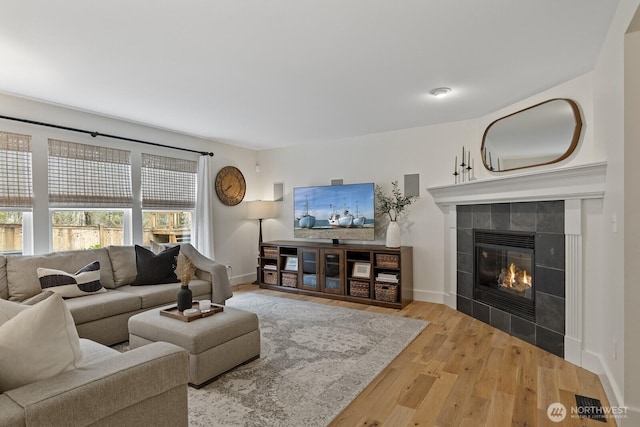 living room with a fireplace, baseboards, and wood finished floors