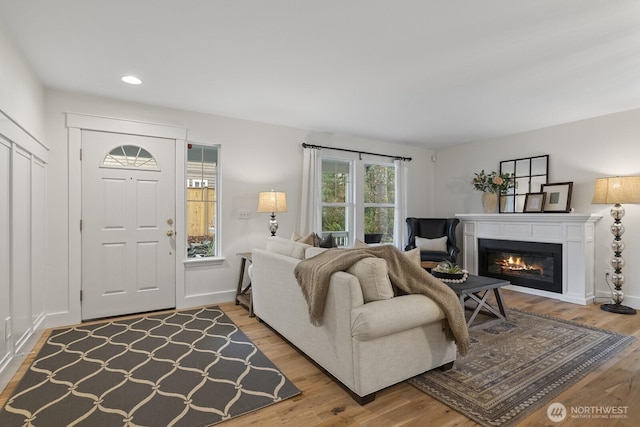 living area featuring recessed lighting, baseboards, wood finished floors, and a glass covered fireplace