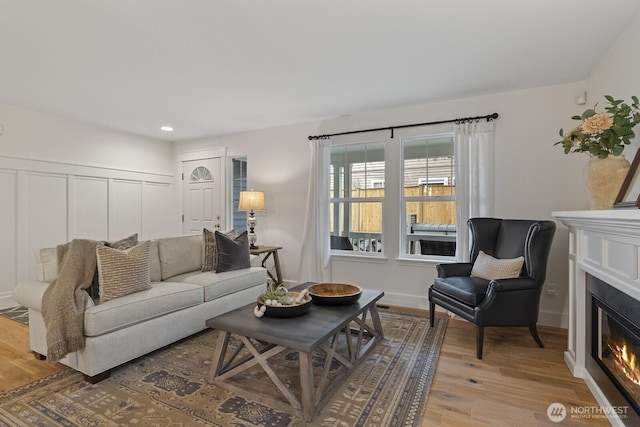 living room with recessed lighting, a glass covered fireplace, and light wood-style floors