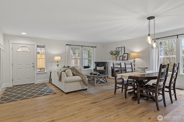 dining room featuring light wood-type flooring, a healthy amount of sunlight, baseboards, and recessed lighting