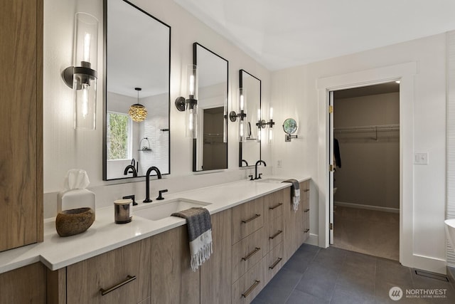 full bathroom with double vanity, tile patterned flooring, a walk in closet, and a sink