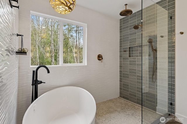 full bath with a healthy amount of sunlight, tile walls, a freestanding bath, and tiled shower