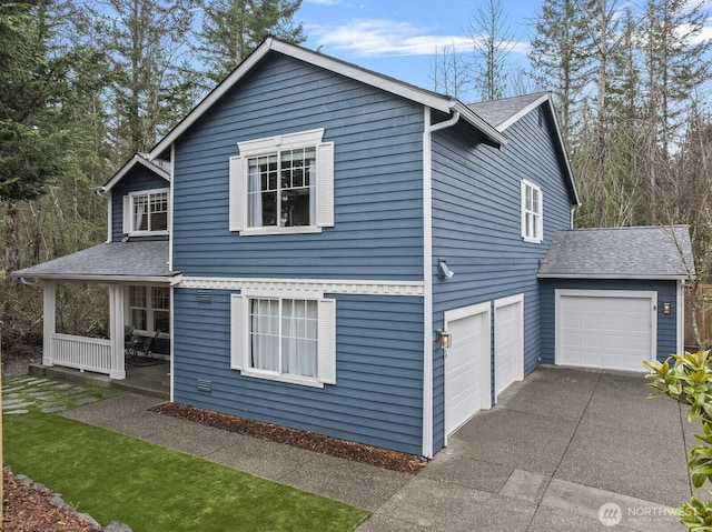 view of side of property with driveway, covered porch, and a shingled roof