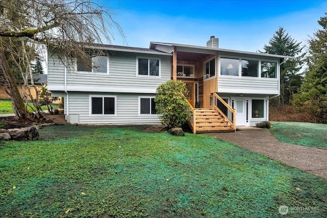 split foyer home featuring driveway, a chimney, a front yard, and a sunroom