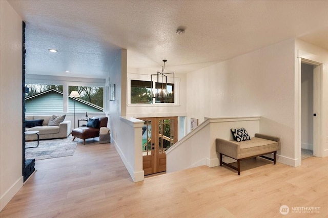 living area featuring a textured ceiling, a chandelier, wood finished floors, and baseboards