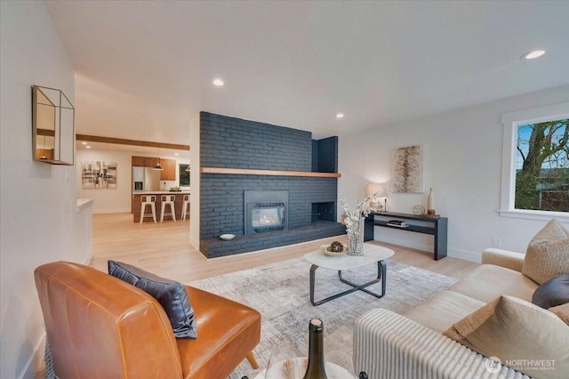 living area featuring a brick fireplace, baseboards, wood finished floors, and recessed lighting