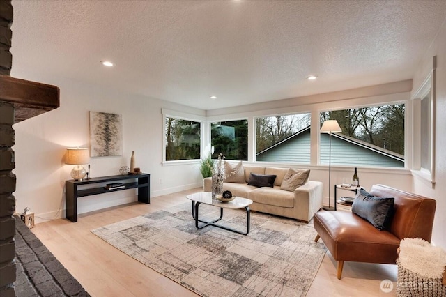 living area with light wood-style floors, recessed lighting, a textured ceiling, and baseboards