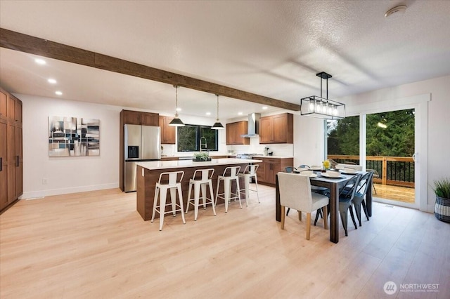 dining space with light wood finished floors, plenty of natural light, baseboards, and beamed ceiling