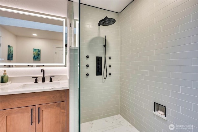 full bathroom featuring marble finish floor, tiled shower, and vanity