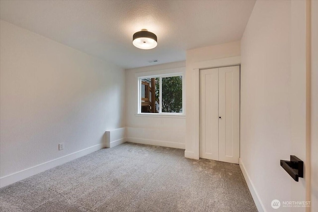 unfurnished bedroom featuring carpet floors, a closet, visible vents, and baseboards