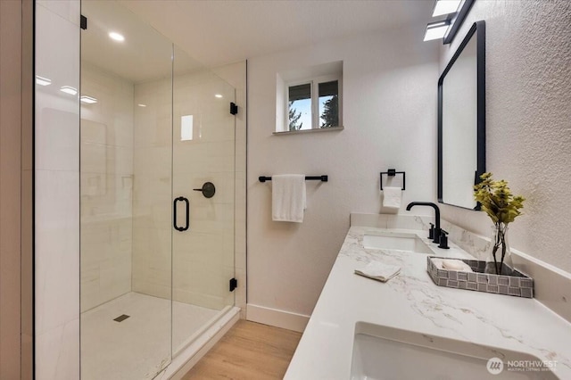 bathroom featuring a stall shower, wood finished floors, vanity, and baseboards